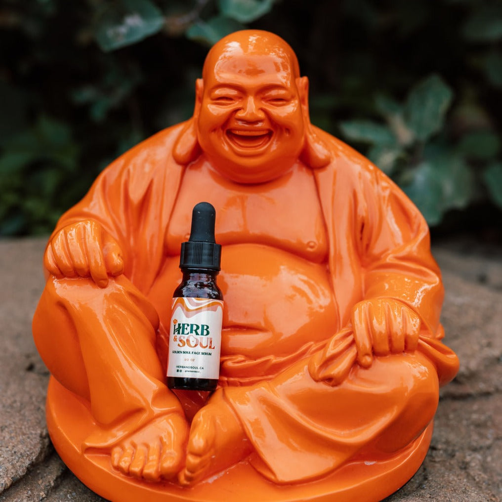 Herb & Soul Golden Soul Face Serum container seating on a figure of Buddha